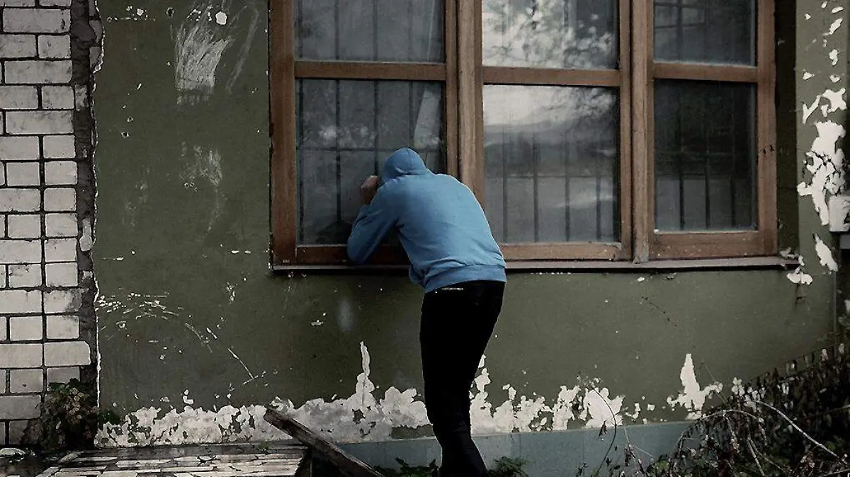 Hombre mirando por la ventana de una casa